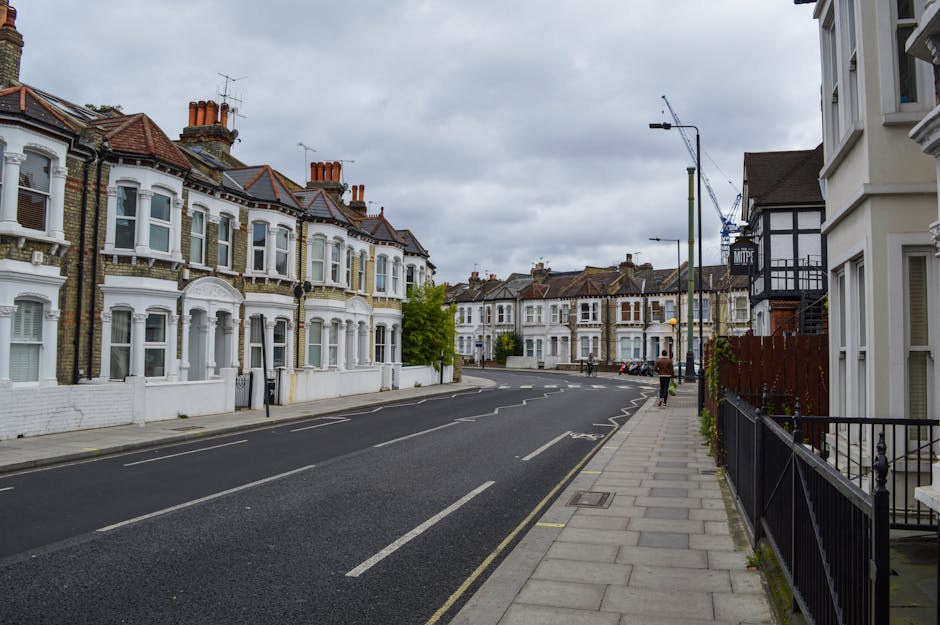 A row of Victorian terraced houses constructed with traditional yellow and brown brickwork, featuring uniform sash windows with white frames and small decorative ledges beneath each window. The buildi